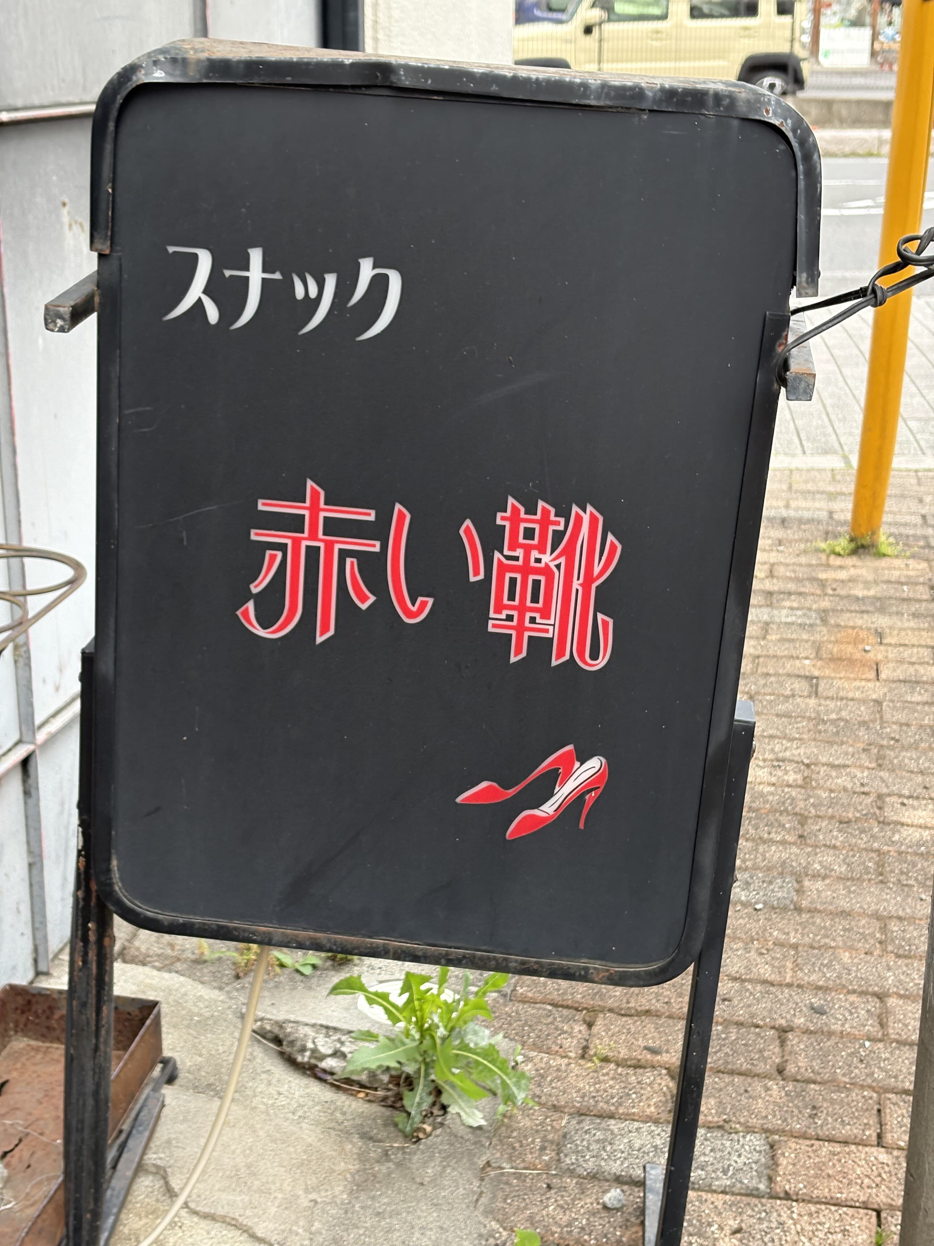 黒い置き看板に赤文字を浮かべた「スナック 赤い靴」