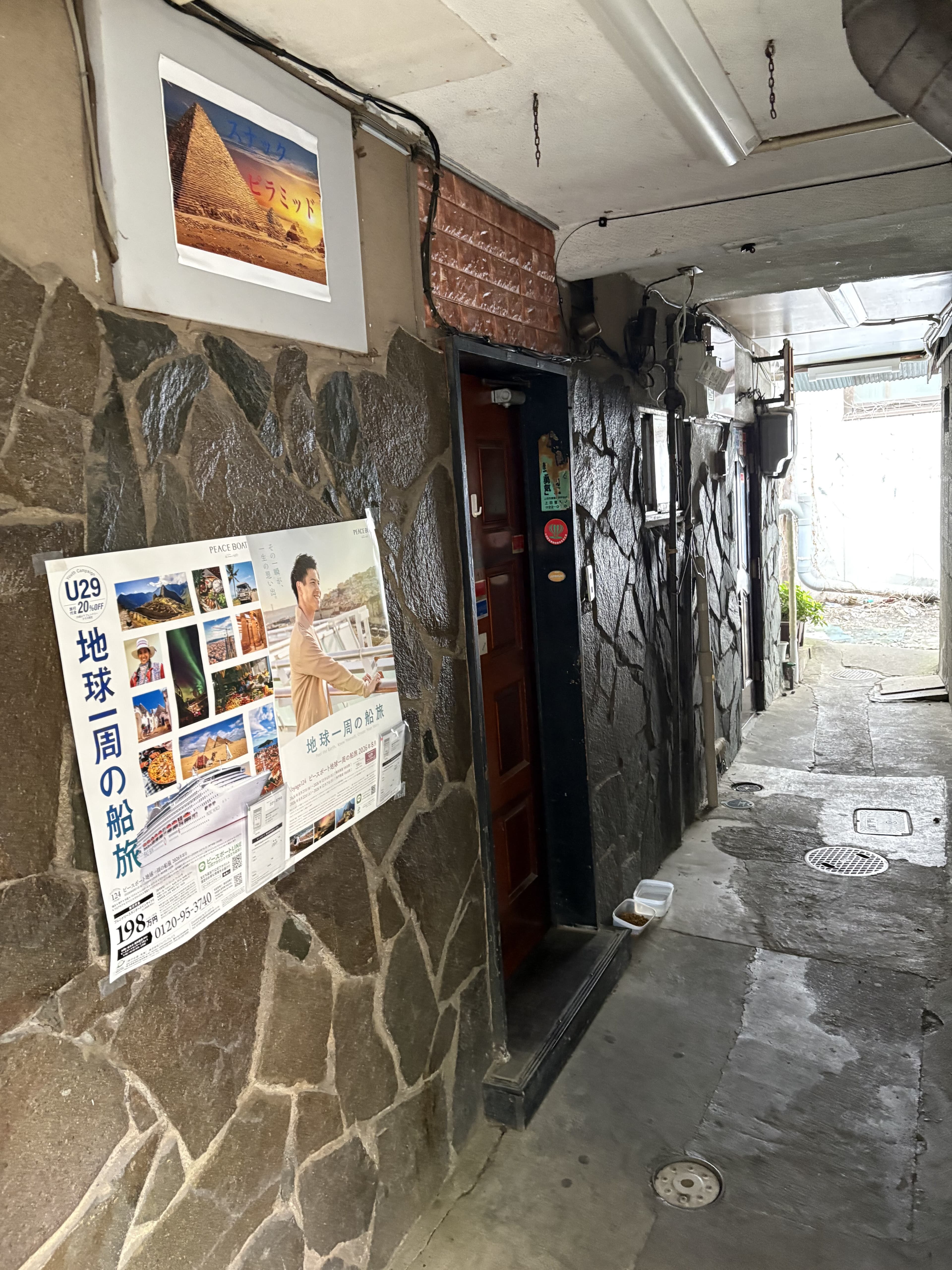 細い通路の奥に見える「ピラミッド」の壁面看板