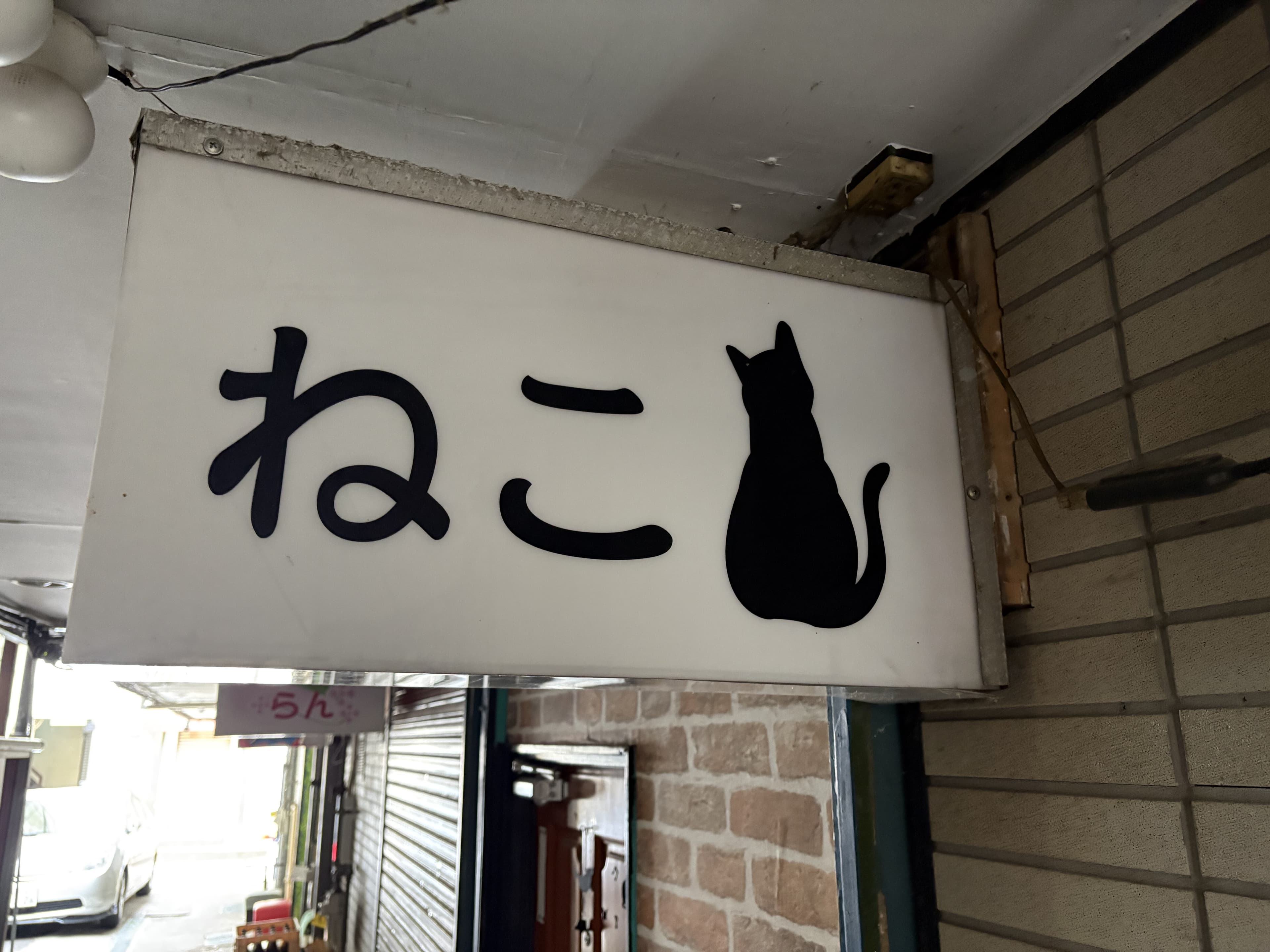 黒猫シルエットを添えた白い「ねこ」看板