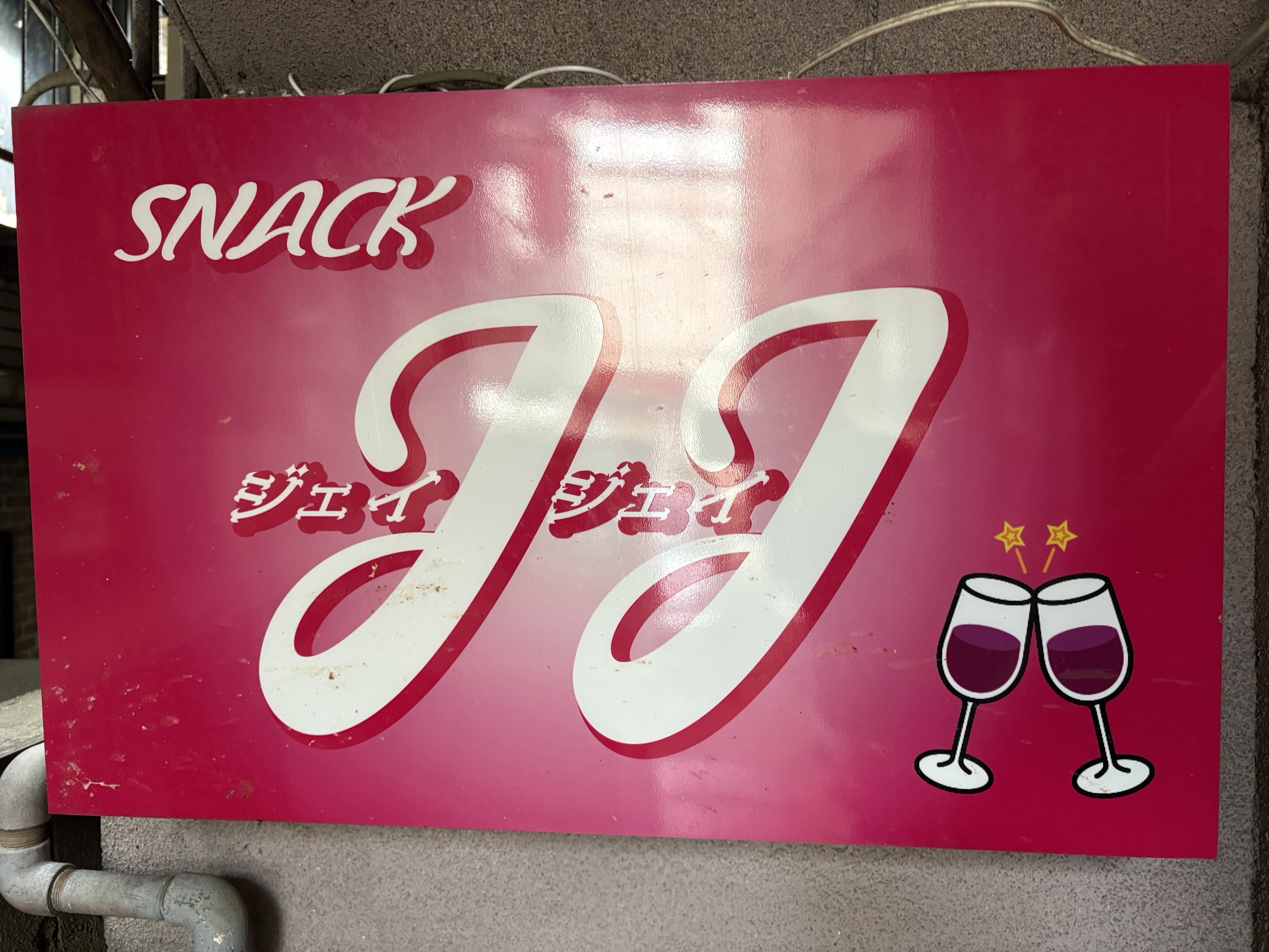 ピンク地にグラスのイラストを添えた「SNACK JJ」看板
