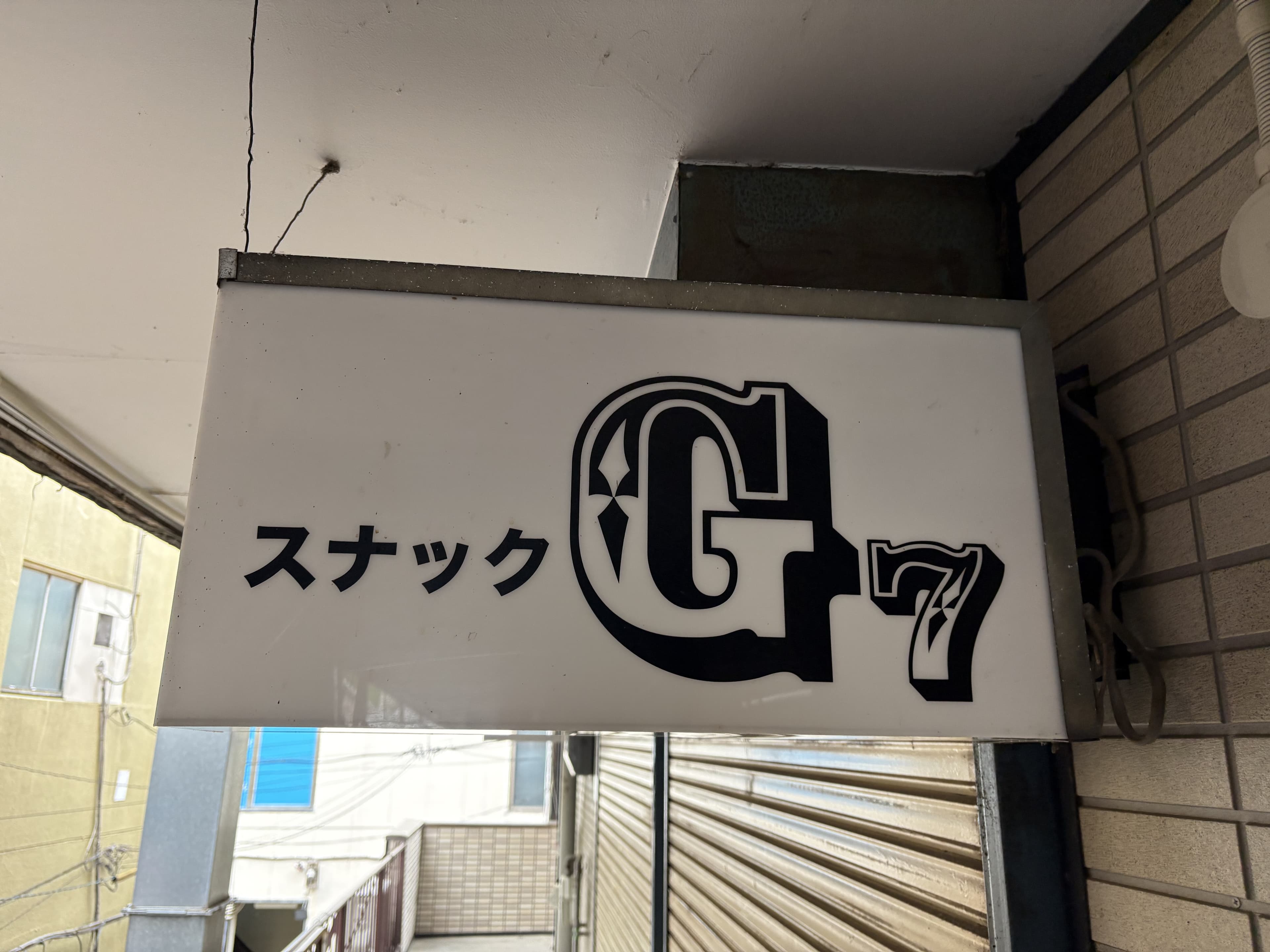 白地に大きな「G7」ロゴを置いたスナック看板