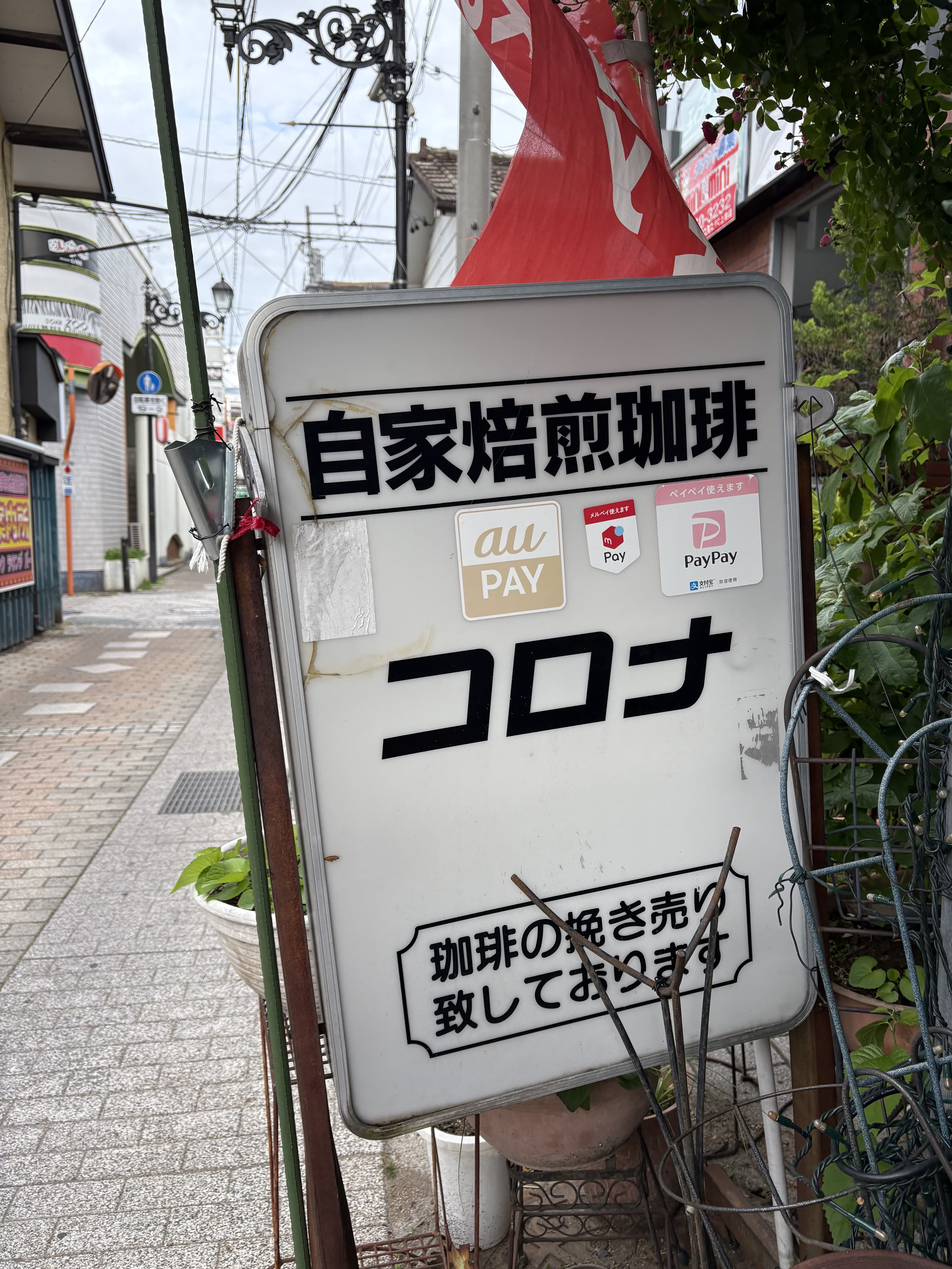 路地に立つ「自家焙煎珈琲 コロナ」の白い看板