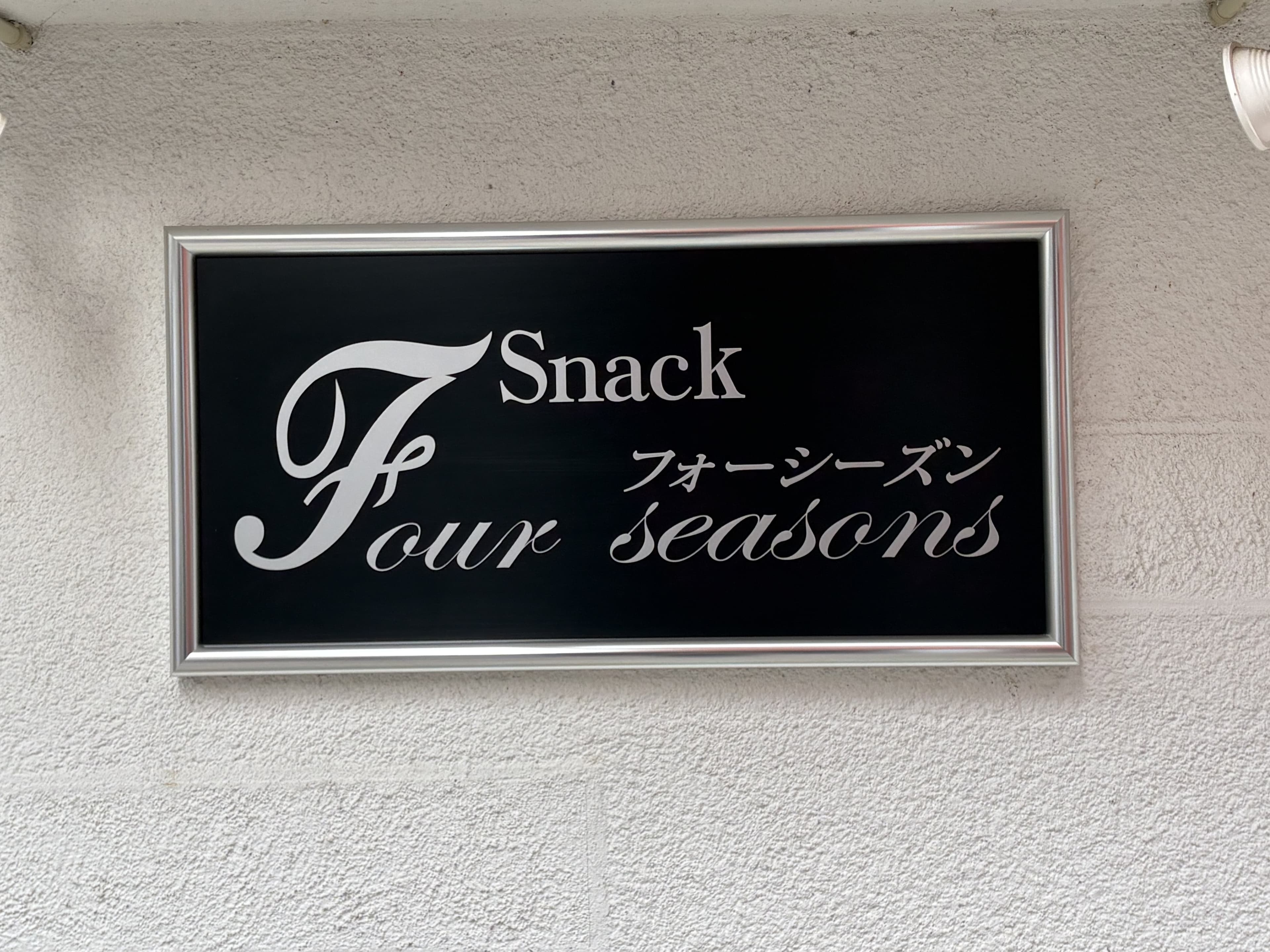 黒地に白い筆記体を置いた「Snack Four Seasons」看板