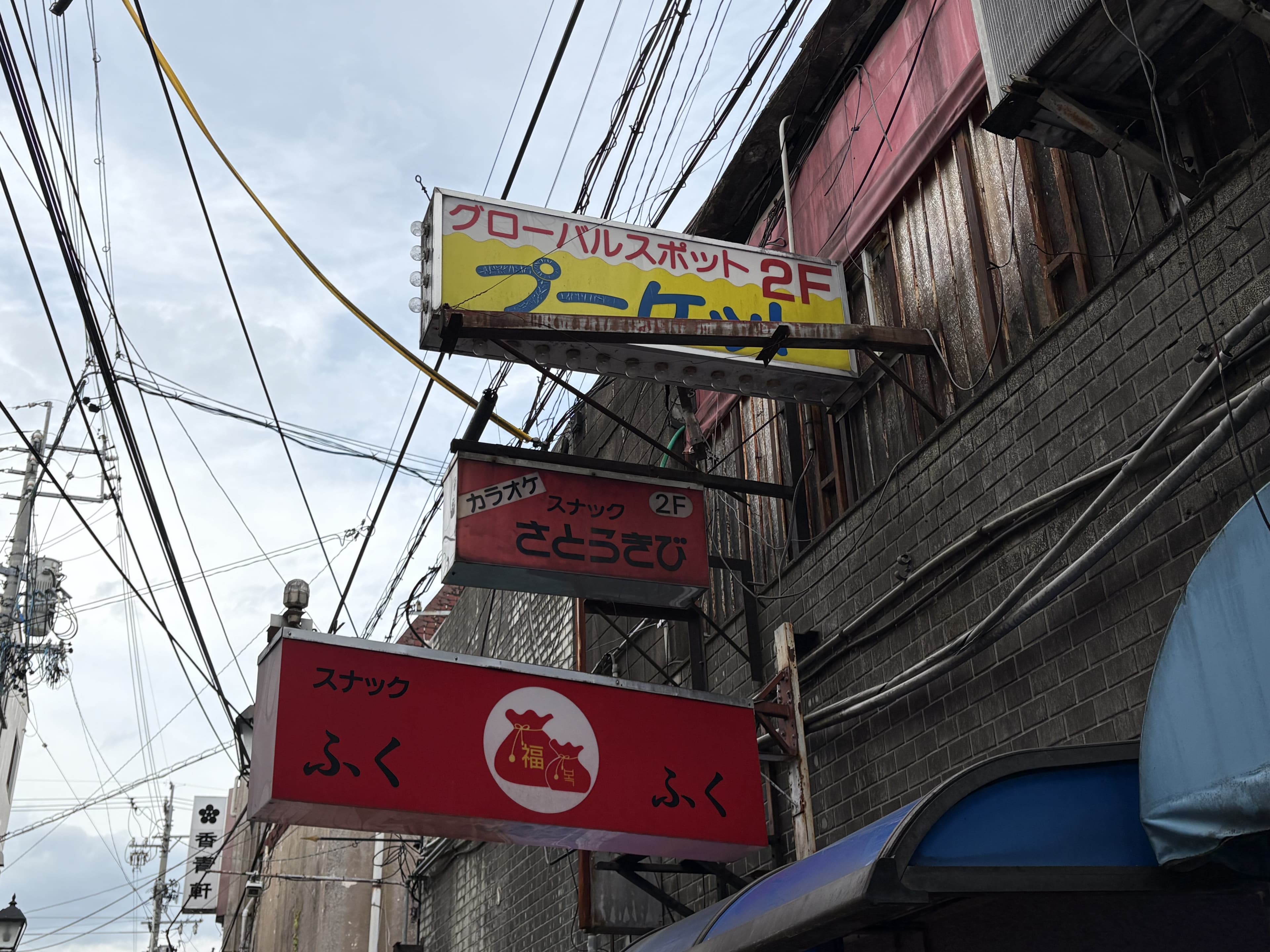 路地上に重なる「ブーメラン」「ふくふく」などの赤い看板群