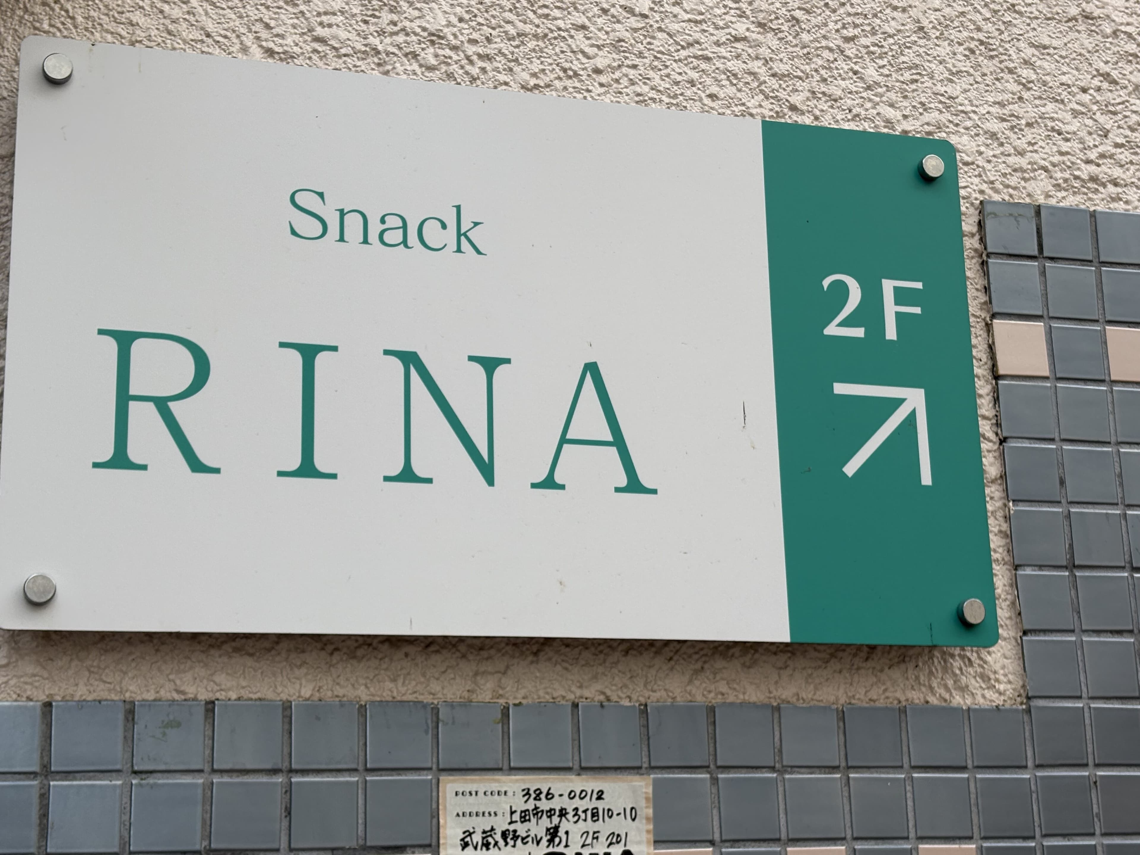 白地と緑帯で2階を示す「Snack RINA」看板