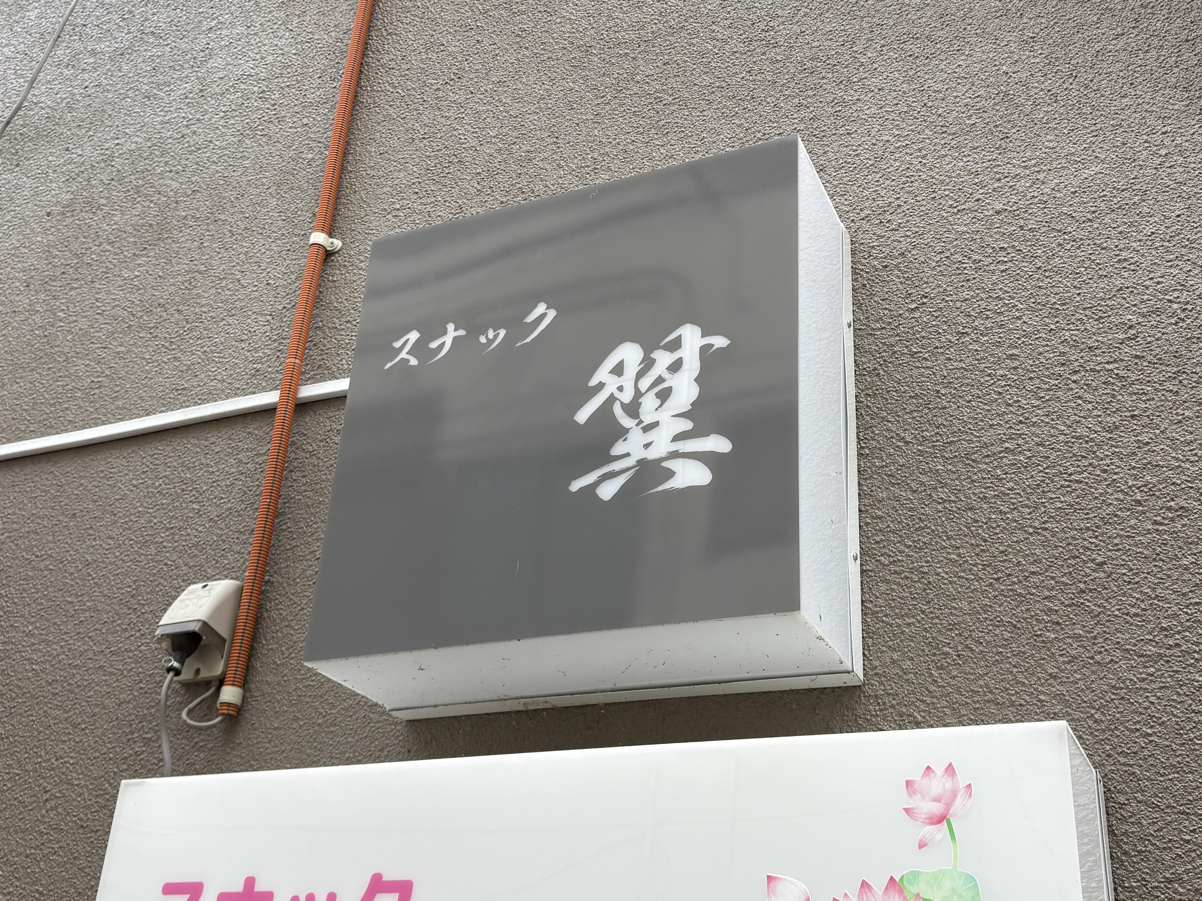灰色の箱看板に白い筆文字を置いた「スナック 燈」看板