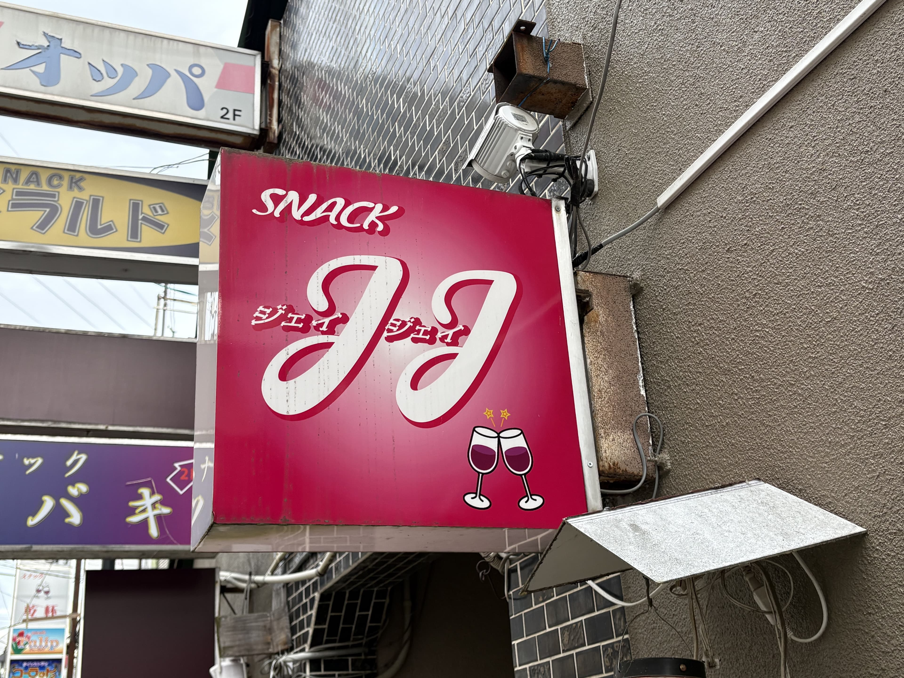 「JJ」「オッパ」「エメラルド」「ツバキ」が重なる路地の袖看板群