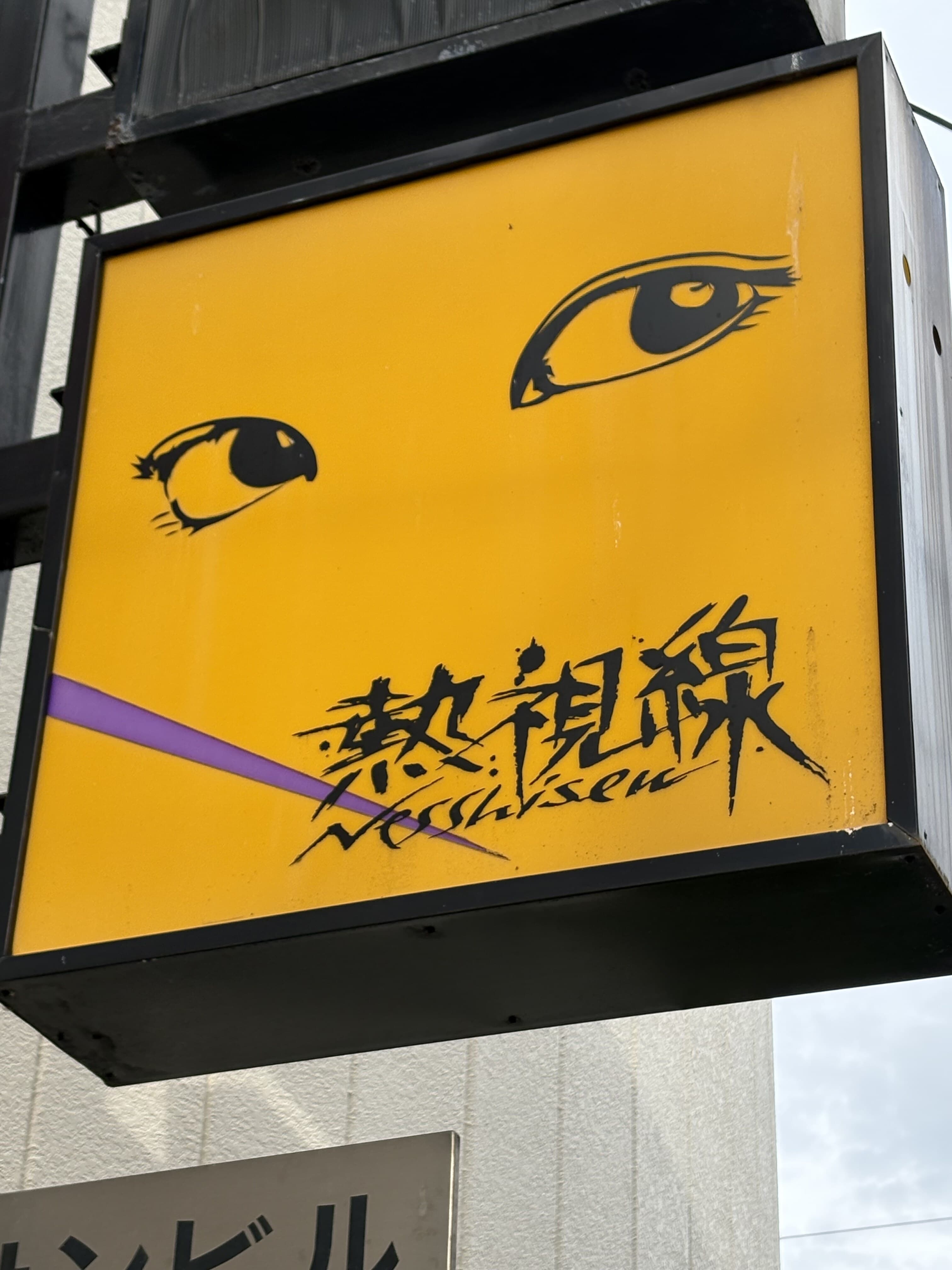 黄色い箱看板に目元のイラストを置いた「熱視線」看板
