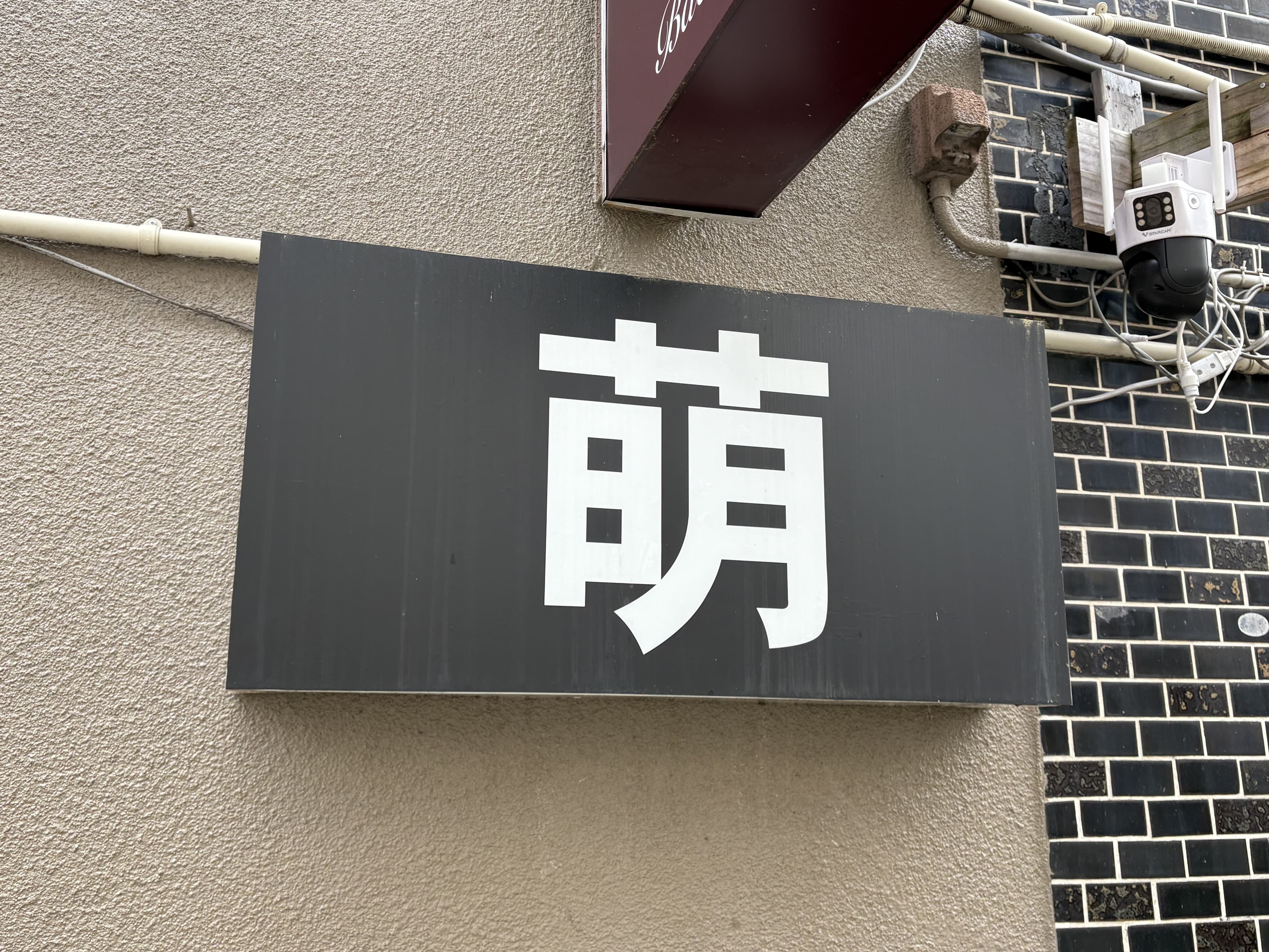 黒地に大きな白文字を置いた「萌」看板