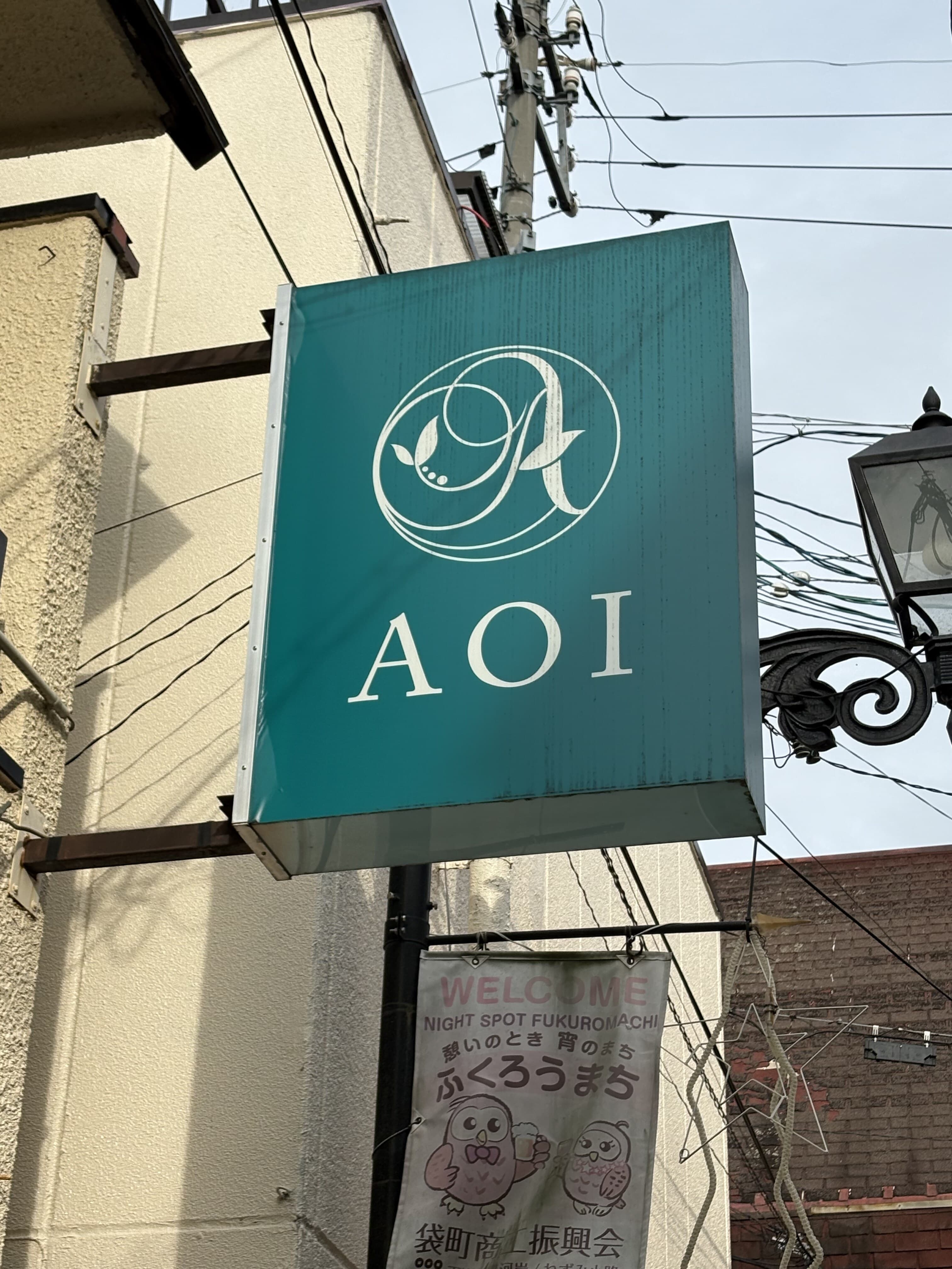 緑の箱看板に白いロゴを置いた「AOI」看板