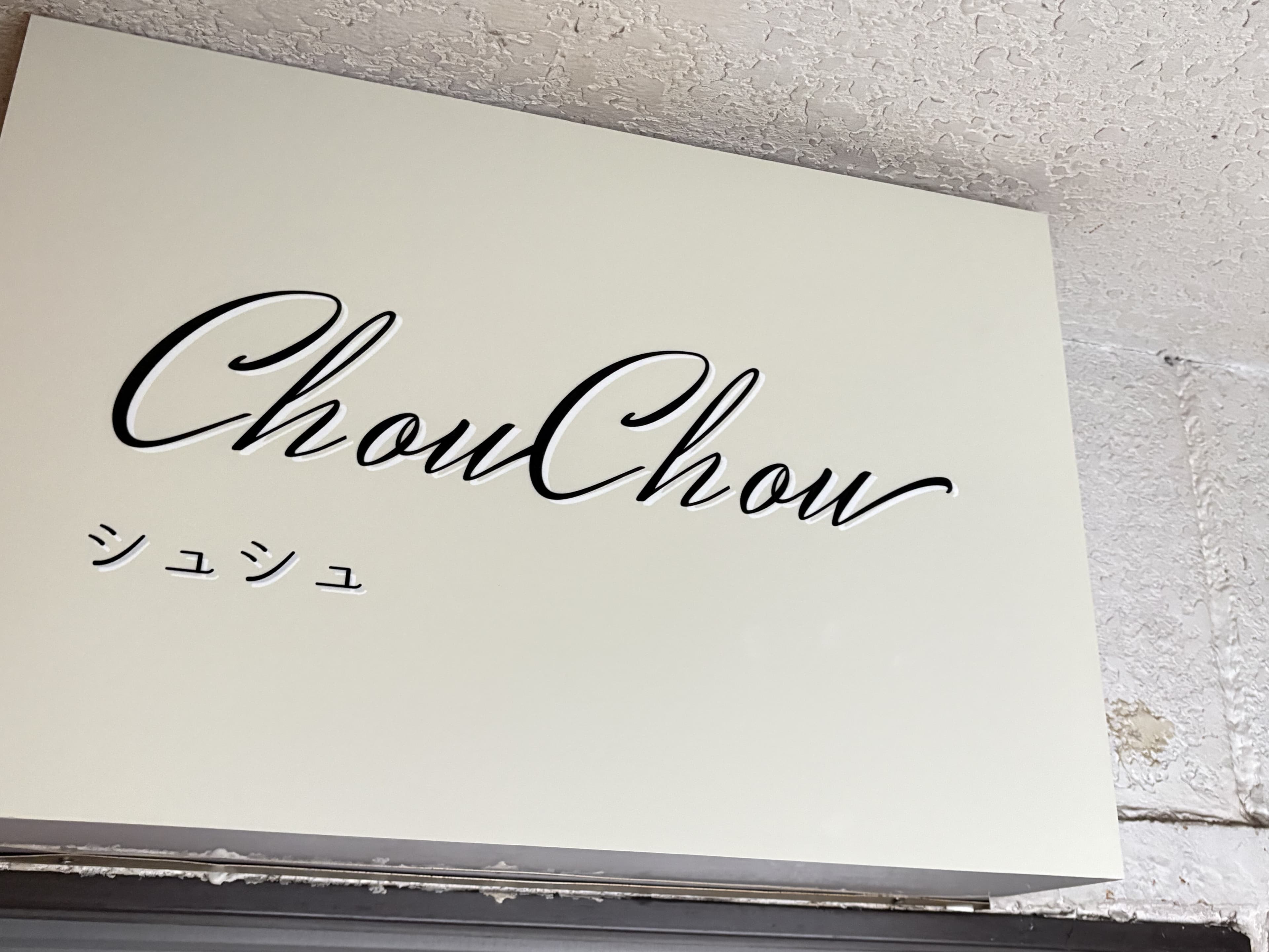 白い面板に筆記体を置いた「ChouChou」看板