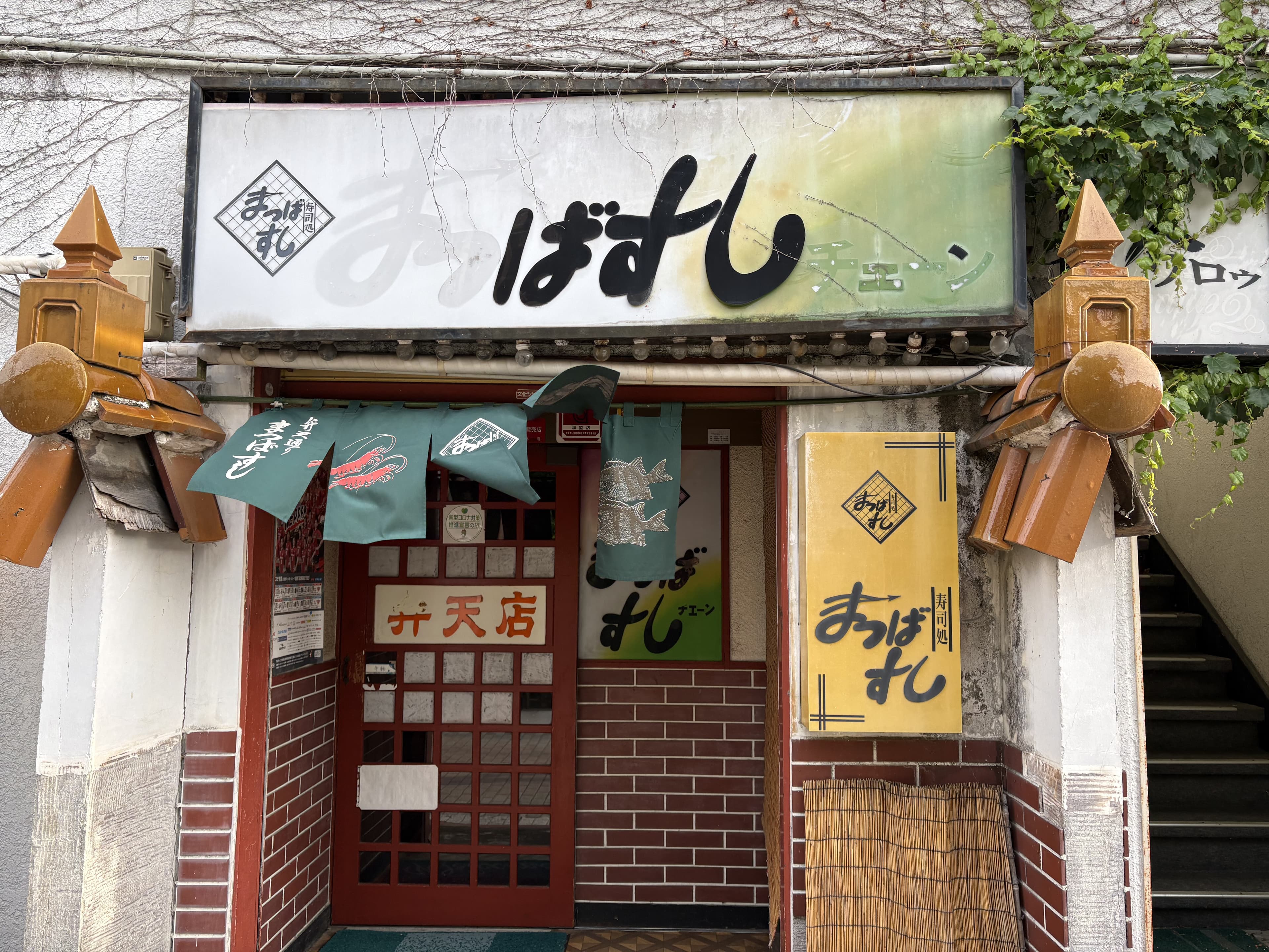 小さな店構えに重なる「まつばすし」看板群
