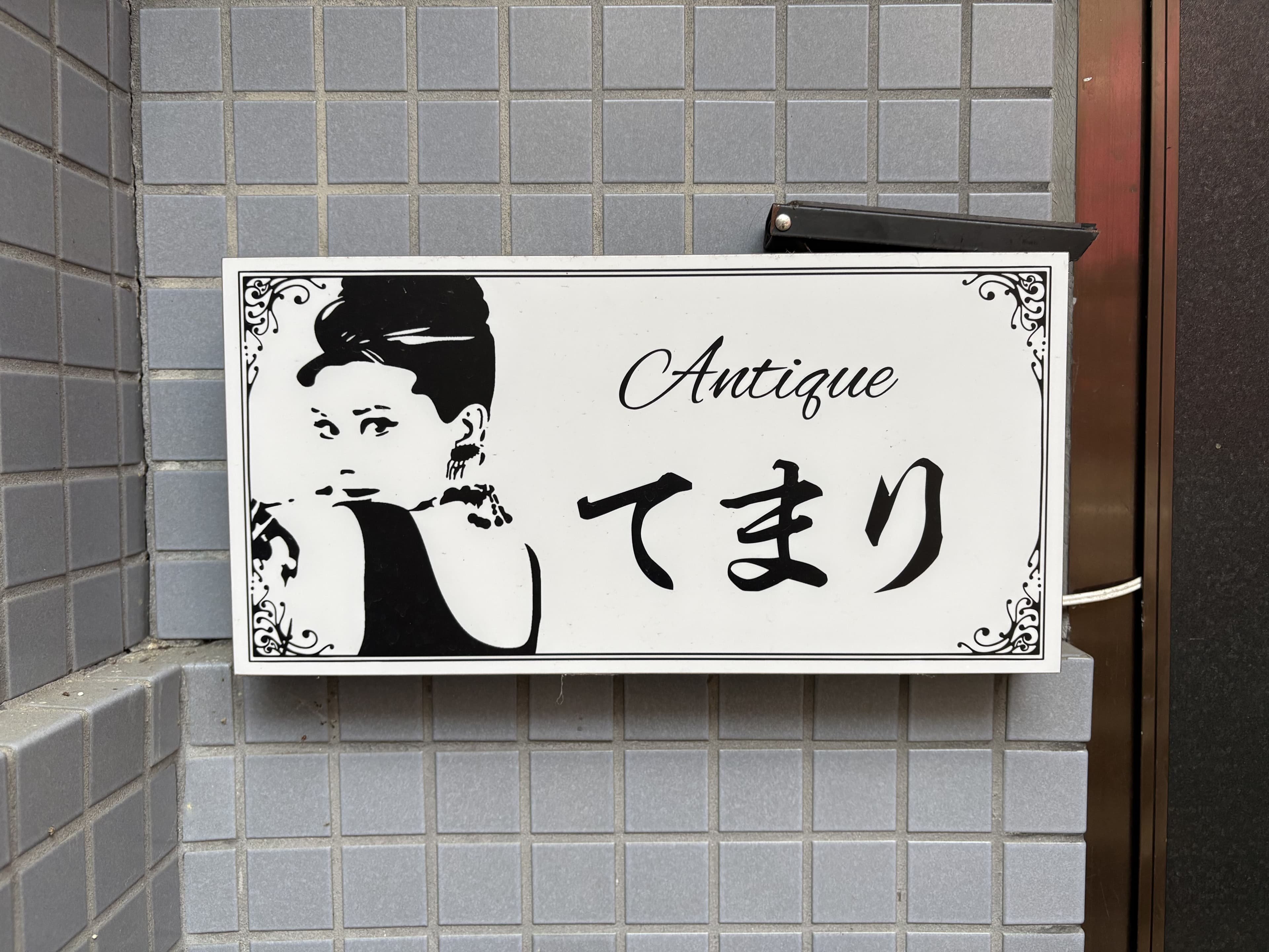 富山・桜木町の白い小プレートに残る「てまり」の横顔ロゴ