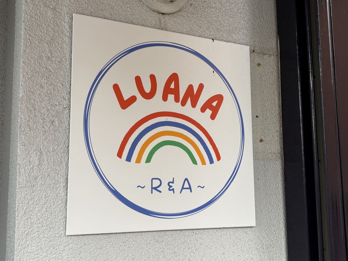 虹の線で囲んだ「LUANA」の丸看板