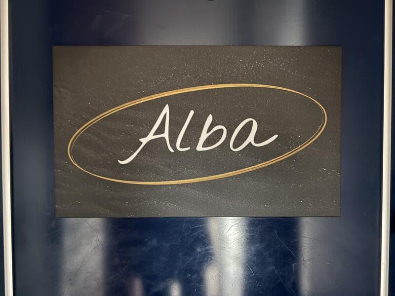 暗色の楕円に金縁の「Alba」